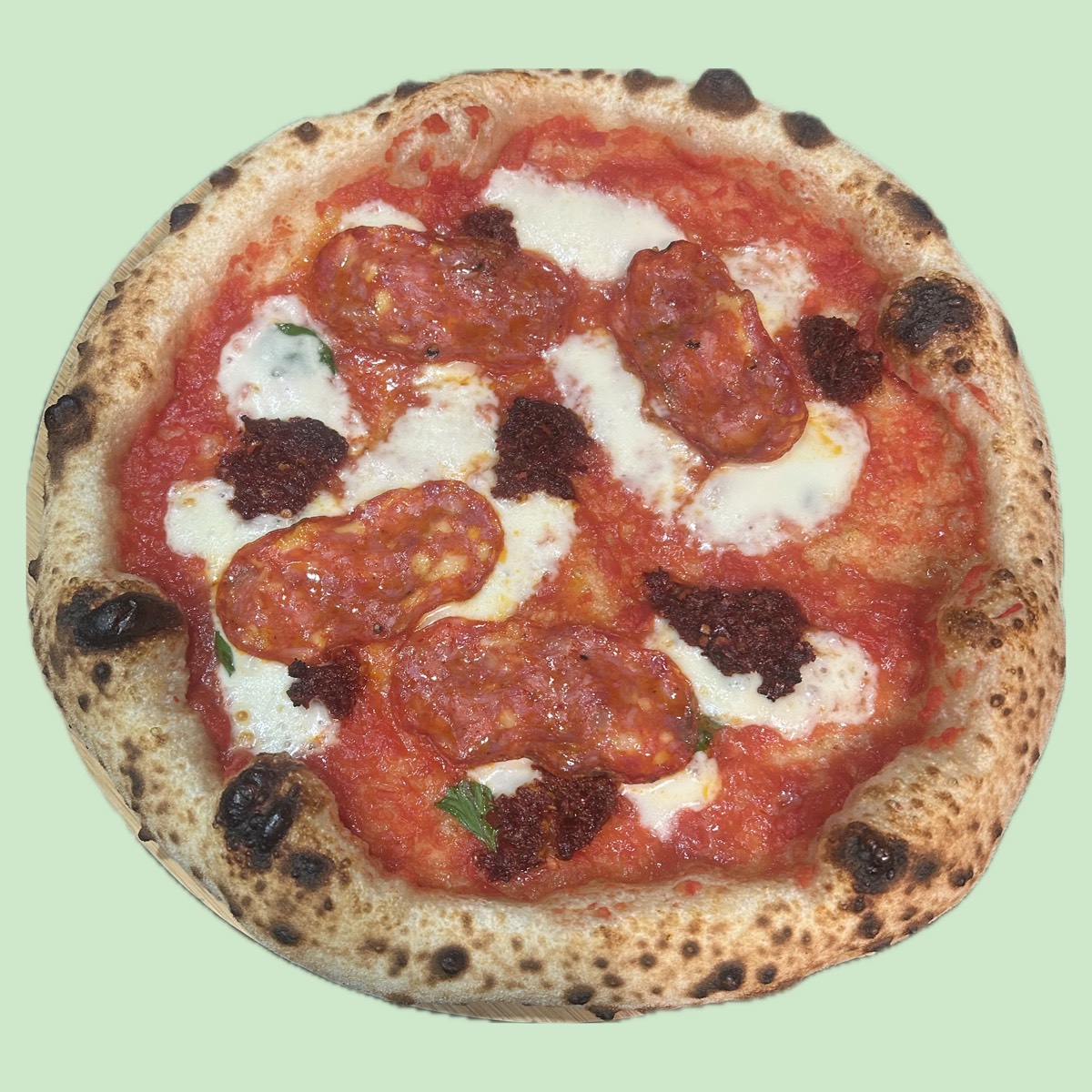 Pizza neapolitańska z salami i ndują, z grubym wypieczonym rantem w ciemne cętki, prosto z pieca